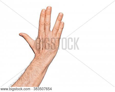 Hand of caucasian middle age man over isolated white background greeting doing Vulcan salute, showing back of the hand and fingers, freak culture
