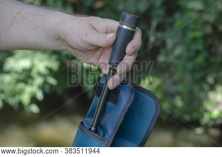 A Mans Hand Removes The Baitcasting Rod From The Case. Preparation For Fishing With A Carbon Spinnin