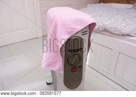 A Dangerous Hazardous Situation With Mobile Oil Heater Covered With A Towel, That Is Dryin On A Hot 