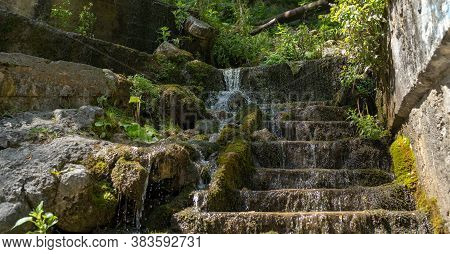 Close Up Of Mountain Stream Flowing Down Stone Steps In Summertime. Manmade Decorative Waterfall Flo