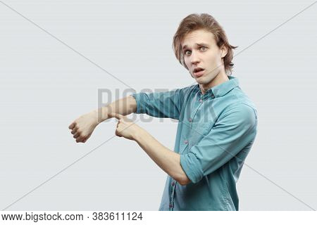 Portrait Of Worry Handsome Long Haired Blonde Young Man In Blue Casual Shirt Standing And Showing Ti