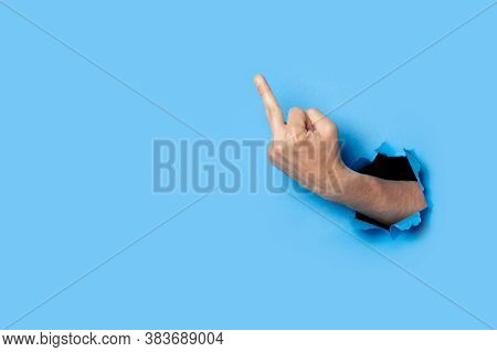 Hand Shows The Gesture Of The Middle Finger On A Blue Background. Offensive Gesture, Fuck Off, Leave