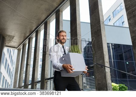 An Unhappy Young Manager In A White Shirt Is Fired From His Job. A Sad Worker Sits On The Steps Of A