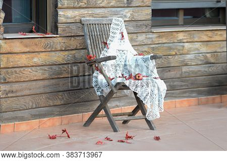 Autumn View Of The Terrace Of A Wooden House. Folding Wooden Chair With Knitted Blanket, Ripe Red Ap