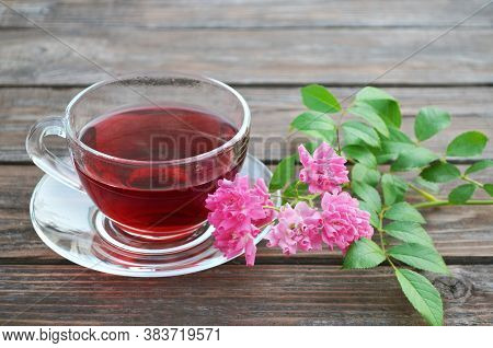 Cup Of Freshly Made Hot Tea And Pink Roses On A Old Wooden Table.
