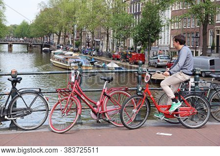 Amsterdam, Netherlands - July 10, 2017: Cyclist Crosses Herengracht Canal In Amsterdam, Netherlands.