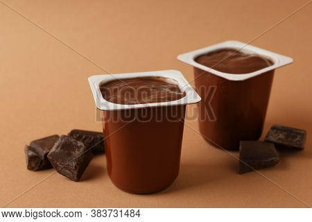 Plastics Cups Of Chocolate Yogurt On Brown Background