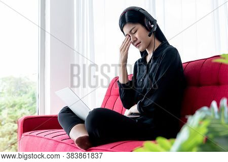 Portrait Images Of Asian Attractive Woman Wearing Earphone Sitting On The Red Sofa, She Has Eyestrai