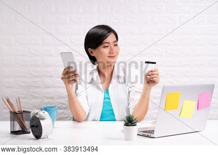 Happy Woman Use Smart Phone And Credit Card At Office