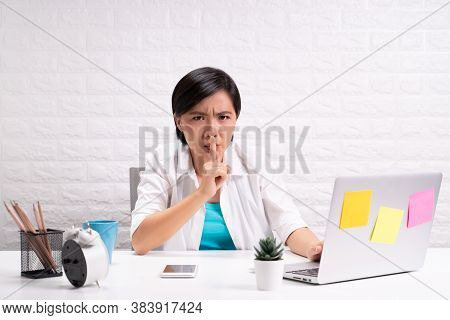 Woman Sitting At Home Office Using Laptop And Show A Quiet Gesture