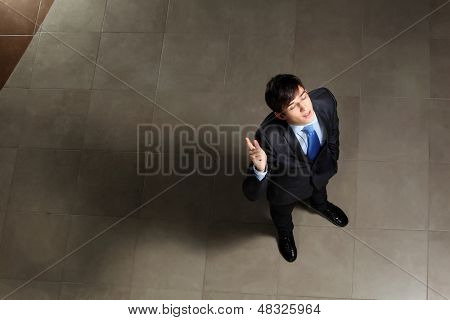 Image of young businessman with his eyes closed thumb up. Top view