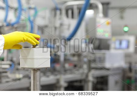 hand in yellow glove pressing button - starting industrial process
