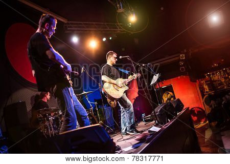 Band performs on stage, rock music concert in a nightclub. Warning - authentic shooting with high iso in challenging lighting conditions. A little bit grain and blurred motion effects.