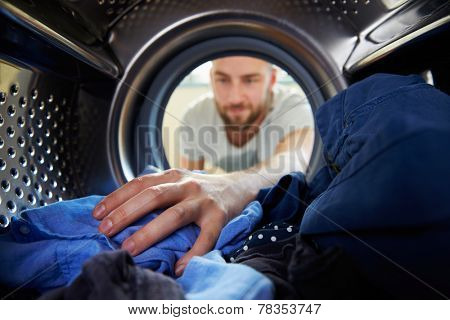 Man Doing Laundry Reaching Inside Washing Machine