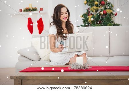 Pretty brunette shopping online with laptop at chistmas against snow