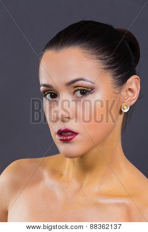 Girl with a professional makeup posing on a gray background.