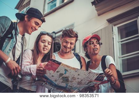 Multiracial friends tourists with map in an old city 