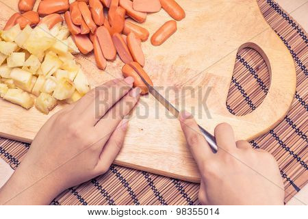 Preparing sausage and vegetables woman hands vintage tone.