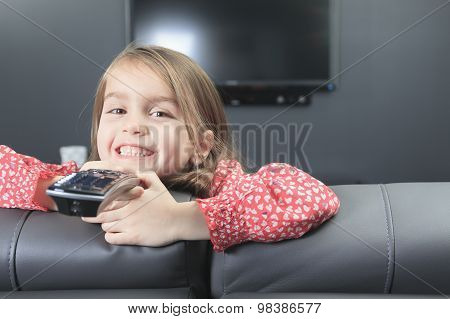 cute little girl with remote control in front of TV.