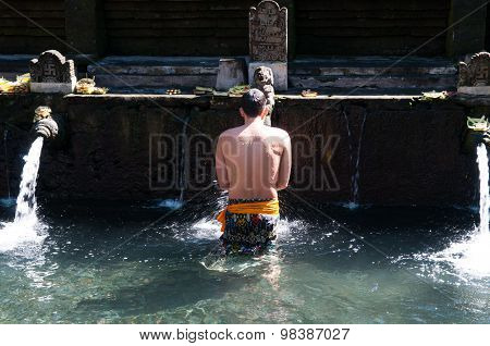 A man bathes in holy water pool in Tirta Empul temple