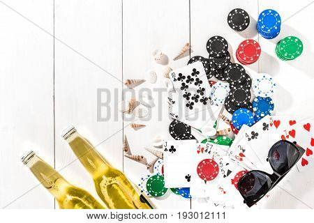 Gambling. Poker chips, cards and two bottles of beer on white wooden table. Top view. Copyspace. Poker. Summer