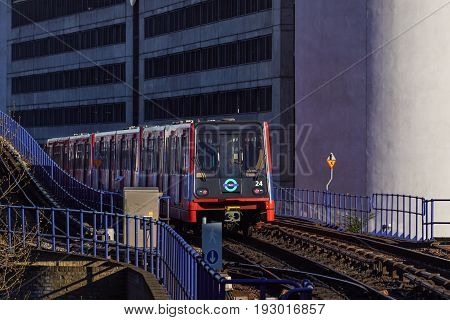 LONDON, ENGLAND - MAY 5, 2017: Canary Wharf, DLR station in London, UK. DLR train leaving the station on a bright day