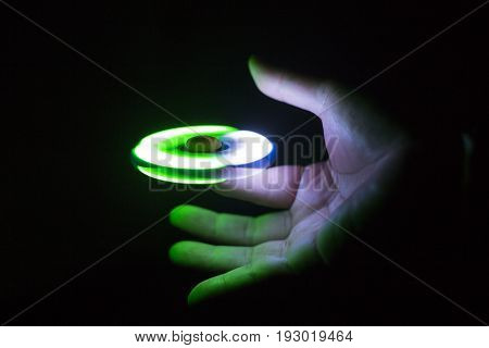 Play Fidget spinner spinning and Hand on dark background With Ligtht