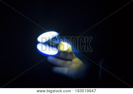 Play Fidget spinner spinning and Hand on dark background With Ligtht