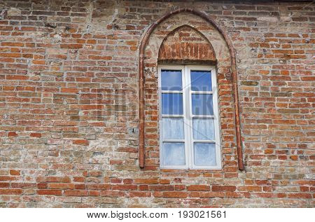 Castle window in a medieval style. Double arched window on a facade of medieval wall. Biforium - ancient window with column, old architecture element of Roman and Gothic styles.