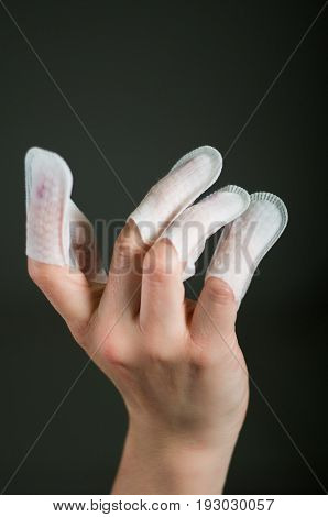 Close up of young woman wearing nails protector in her nails, hand and ideal clean manicure, in a black background.