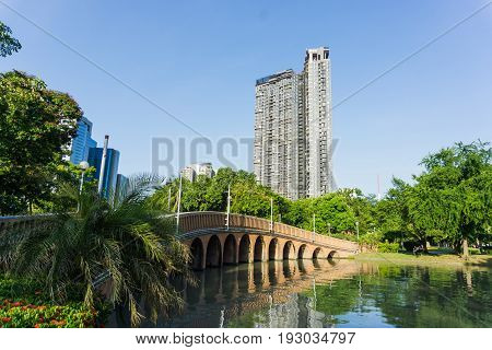 Bridge over the lake and high building at CHATUCHAK PARK.