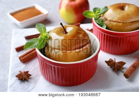 Cocottes with tasty baked apples and cinnamon on kitchen table, closeup