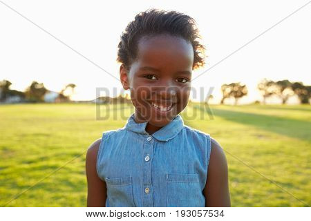 African elementary school girl smiling in a park, close up