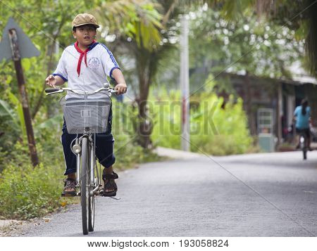 An Binh Island, Vietnam - March 25, 2017 : Vietnamese pioneers go home from school by bicycles on An Binh island, Vinh Long, Vietnam