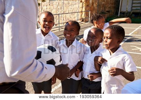 Teacher with ball and kids in elementary school playground
