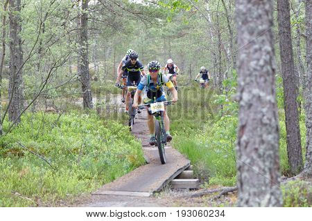 STOCKHOLM SWEDEN - JUNE 11 2017: Female mountain bike cyclist in the forest cycling over a bridge in the forest at Lida Loop Mountain bike Race. June 11 2017 in Stockholm Sweden
