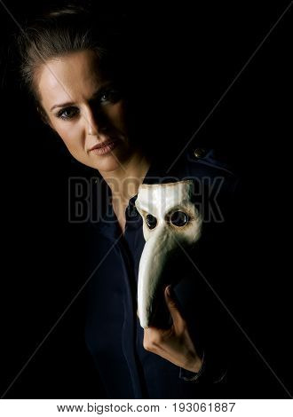 Coming out into the light. woman in the dark dress isolated on black showing Venetian mask