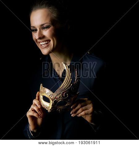 Coming out into the light. happy woman in the dark dress isolated on black with Venetian mask