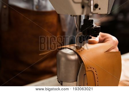 Close up of a shoemaker using sewing machine in workshop