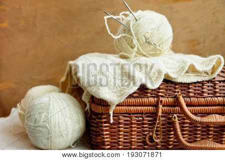 Old vintage wicker hobby chest with white wool clews needlework on rustic wood background knitting crafts concept banner header image for websites