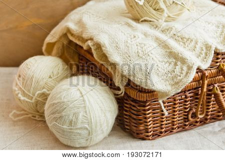 Old vintage wicker hobby chest on linen fabric with white wool clews needlework on rustic wood background knitting crafts concept banner header image for websites