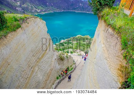 QUITO, ECUADOR - NOVEMBER, 25 2016: Unidentified people walking in a path to enjoy the beautiful and amazing view of lake with a beautiful magenta color of the Quilotoa caldera, . Quilotoa is the western volcano in Andes range and is located in andean reg