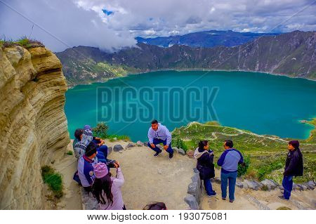 QUITO, ECUADOR - NOVEMBER, 25 2016: Unidentified people taking pictures and enjoying the view of lake with a beautiful magenta color of the Quilotoa caldera. Quilotoa is the western volcano in Andes range and is located in andean region of Ecuador.