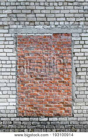 In the brick wall of white brick capped with red brick window. Masonry is uneven. There are chipped. The bottom bricks are dirty.