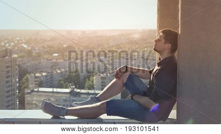 A lonely roofer on the roof of the high-rise at sunset. Courage and adrenaline. Loneliness and calmness