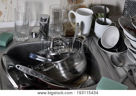 A Huge Pile Of Unwashed Dishes In The Kitchen Sink And On The Countertop