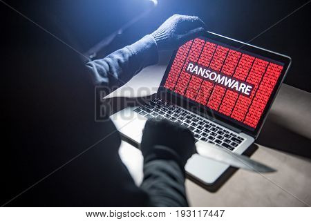 Male hacker threading computer laptop with knife showing on screen with ransomware warning internet security system concept