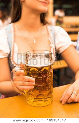 Beautiful young woman in traditional Bavarian Dirndl with beer stein at Munich Oktoberfest