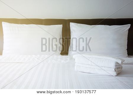 white pillow white blanket and white towel on bed in bedroom with lighting upper left side