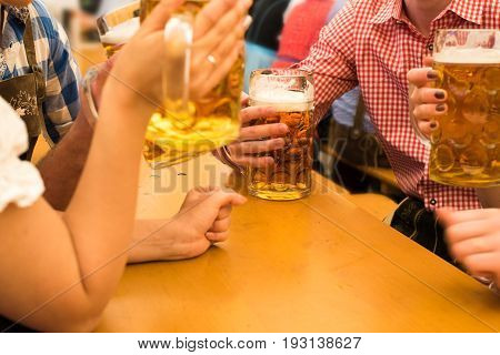 Girls in traditional Dirndl dresses are drinking beer and having fun with their friends at the Oktoberfest in Munich